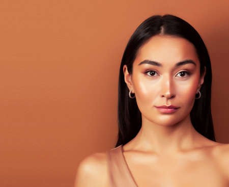 young pretty asian woman cheerful smiling posing on warm brown background, lifestyle people conceptの写真素材