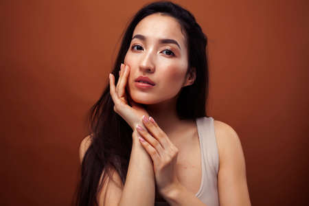 young pretty asian woman cheerful smiling posing on warm brown background, lifestyle people concept