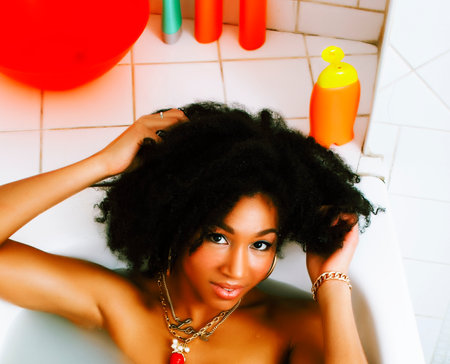 young african-american teen girl laying in bath with foam, wearing swag jewelry flawless, making selfieの写真素材