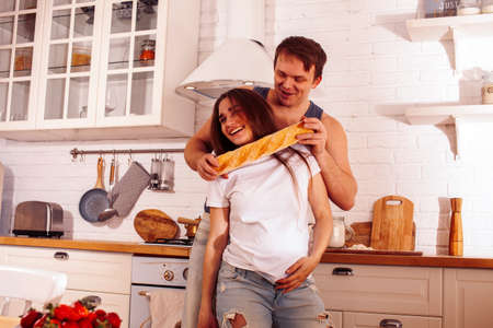 young caucasian couple together having fun on kitchen, woman pregnant, lifestyle people conceptの写真素材