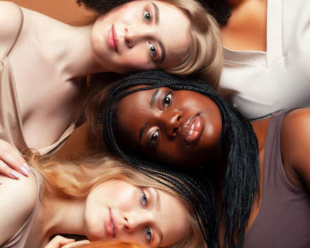 young pretty african and caucasian women posing cheerful together on brown background, lifestyle diverse nationality people conceptの写真素材