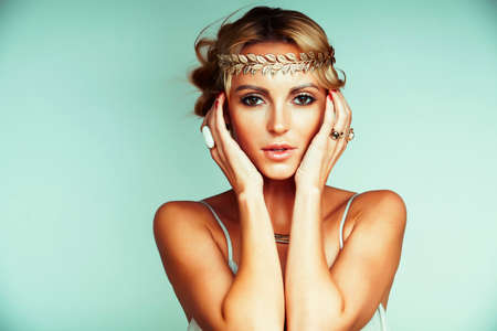 young blond woman dressed like ancient greek godess, gold jewelry close up isolated, beautiful girl hands manicured red nailsの写真素材