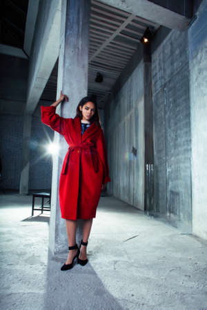 young pretty african american woman in luxury red coat posing fashionable on empty parking building, lifestyle rich people conceptの写真素材