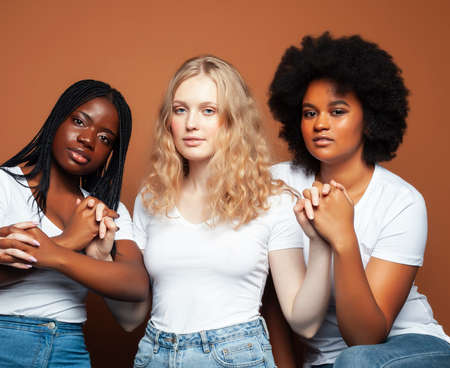young pretty african and caucasian women posing cheerful together on brown background, lifestyle diverse nationality people conceptの写真素材
