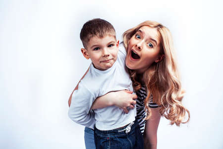 young modern blond mother with cute son together happy smiling family posing cheerful on white background, lifestyle people concept, sister and brother friendsの写真素材