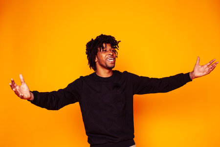 young handsome african american guy student posing cheerful and gesturing on yellow background, lifestyle people conceptの写真素材