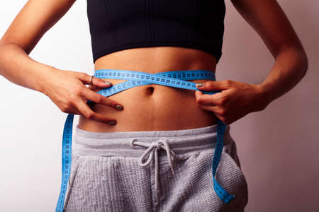 woman measuring waist with tape on knot, african tan isolated