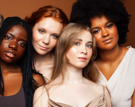young pretty african and caucasian women posing cheerful together on brown background, lifestyle diverse nationality people conceptの写真素材