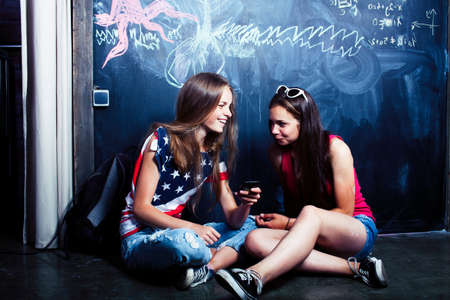 back to school after summer vacations, two teen girls in classroom with blackboard paintedの写真素材