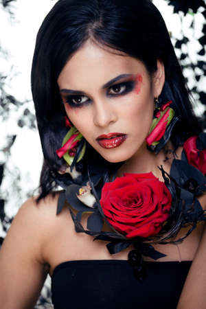 pretty brunette woman with rose jewelry, black and red, bright make up like a vampire closeup red lipsの写真素材