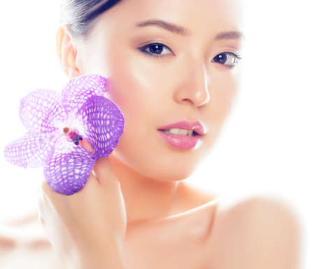 young pretty asian woman with flower purple orchid closeup isolated on white background spa smiling casualの写真素材