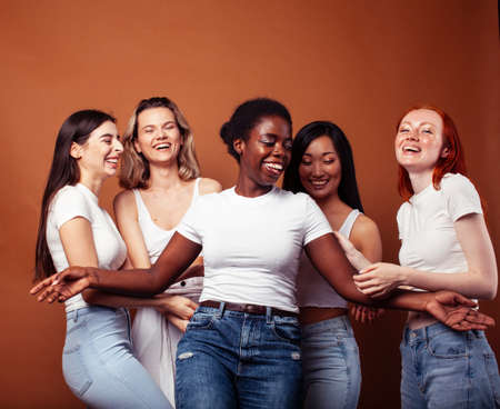young pretty asian, caucasian, african woman posing cheerful together on brown background, lifestyle diverse nationality people conceptの写真素材