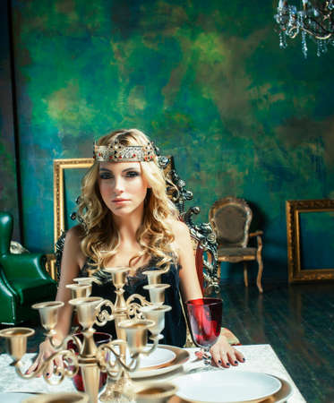 young blond woman wearing crown in fairy luxury interior with empty antique frames total wealth, rich lifestyle conceptの写真素材