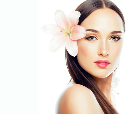 young attractive lady close up with hands on face isolated flower lily brunette spa nude makeup, beauty conceptの写真素材
