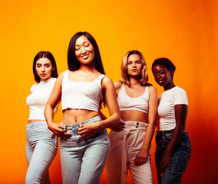 diverse multi nation girls group, teenage friends company cheerful having fun, happy smiling, cute posing on yellow background, lifestyle people concept, african-american, asian and caucasianの写真素材