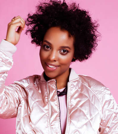 young pretty fashion styled african girl posing emotional cheerful on pink background, lifestyle people conceptの写真素材