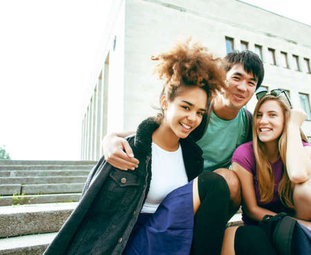 cute group of teenages at the building of university with books huggings, diversity nations, having lunch closeupの写真素材