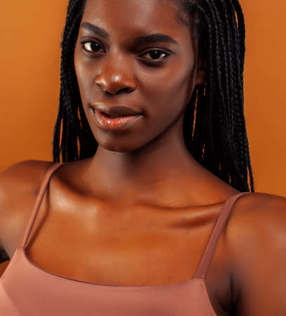 pretty young african american woman with braids posing cheerful gesturing on brown background, lifestyle people conceptの写真素材