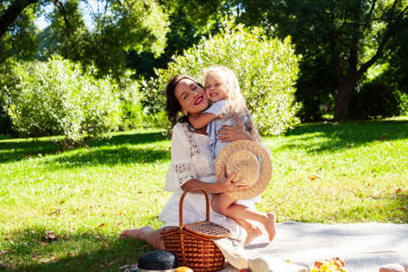 young pretty pregnant brunette woman having fun with her daughter on picnic on green grass in park, lifestyle people conceptの写真素材
