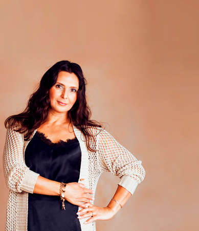 pretty brunette confident mature woman posing cheerful on warm brown background, lifestyle people conceptの写真素材