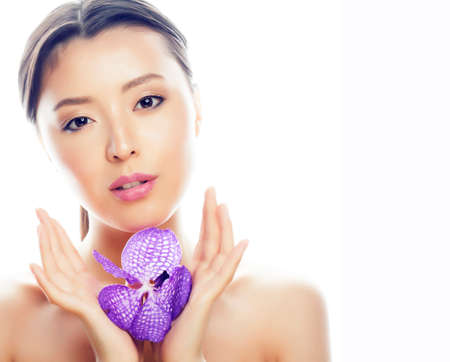 young pretty asian woman with flower purple orchid close up isolated spa smiling casualの写真素材