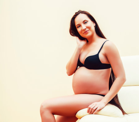 young brunette woman at home in chair pregnant, lifestyle people conceptの写真素材