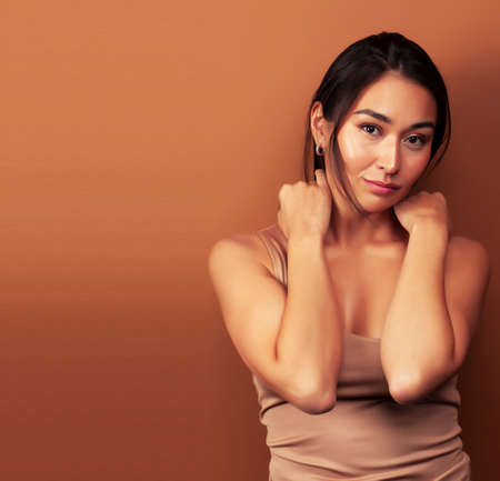 young pretty asian woman cheerful smiling posing on warm brown background, lifestyle people conceptの写真素材