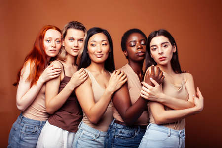 young pretty asian, caucasian, african woman posing cheerful together on brown background, lifestyle diverse nationality people conceptの写真素材