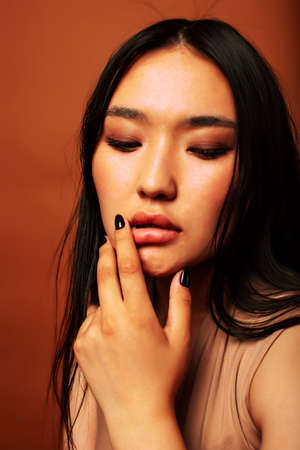 young pretty asian woman cheerful smiling posing on warm brown background, lifestyle people conceptの写真素材