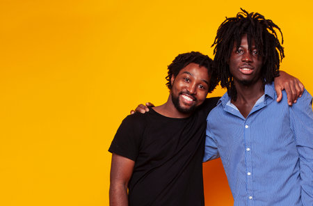 two african american guys posing cheerful together on yellow background, lifestyle people conceptの写真素材