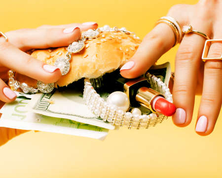 woman hands holding hamburger with money, jewelry, cosmeticの写真素材