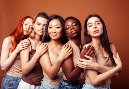 young pretty asian, caucasian, african woman posing cheerful together on brown background, lifestyle diverse nationality people conceptの写真素材