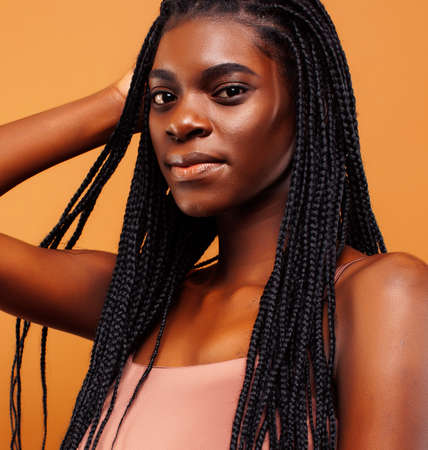 pretty young african american woman with braids posing cheerful gesturing on brown background, lifestyle people conceptの写真素材