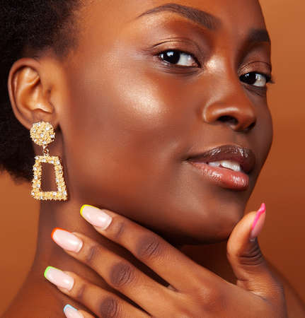 pretty young african american woman with curly hair posing cheerful gesturing on brown background, lifestyle people conceptの写真素材