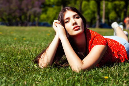 pretty young woman in red dress smiling cheerful in green park on summer sunny day, lifestyle people conceptの写真素材