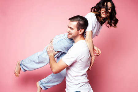 young cheerful caucasian couple together having fun on pink background, guy ang girl modern relationship, lifestyle people conceptの写真素材