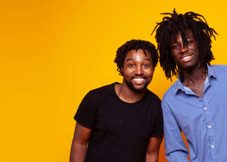 two african american guys posing cheerful together on yellow background, lifestyle people conceptの写真素材