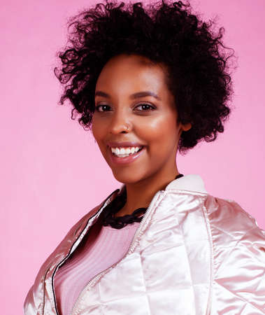 young pretty fashion styled african girl posing emotional cheerful on pink background, lifestyle people conceptの写真素材