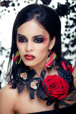 pretty brunette woman with rose jewelry, black and red, bright make up like a vampire closeup red lipsの写真素材