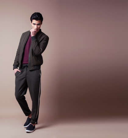 young pretty asian man posing in fashion style on light brown background, lifestyle people conceptの写真素材