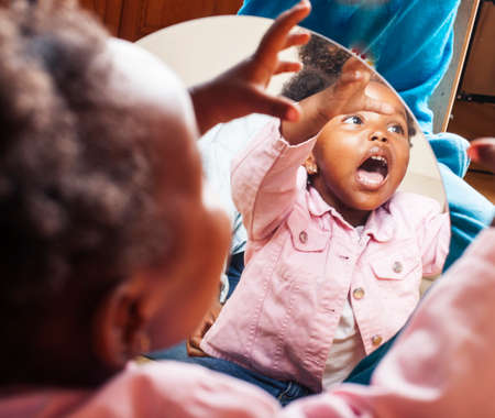 little cute african american girl playing with animal toys at home, pretty adorable princess in interior happy smiling, lifestyle real people conceptの写真素材
