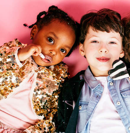 lifestyle people concept: diverse nation children playing together, caucasian boy with african little girl holding candy happy smilingの写真素材