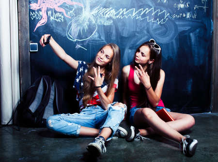 back to school after summer vacations, two teen girls in classroom with blackboard paintedの写真素材