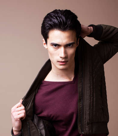 young pretty asian man posing in fashion style on light brown background, lifestyle people conceptの写真素材