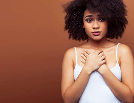 pretty young african american woman with curly hair posing cheerful gesturing on brown background, lifestyle people conceptの写真素材