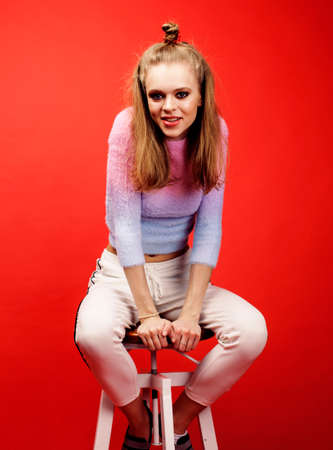 young pretty teenage girl on bright red background, happy smiling lifestyle people concept closeupの写真素材