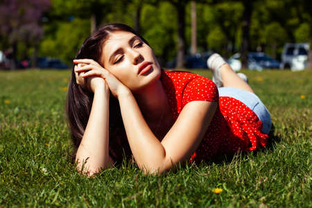 pretty young woman in red dress smiling cheerful in green park on summer sunny day, lifestyle people conceptの写真素材