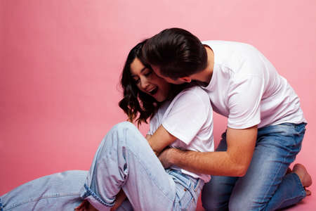 young cheerful caucasian couple together having fun on pink background, guy ang girl modern...