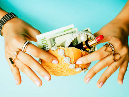 woman hands holding hamburger with money, jewelry, cosmeticの写真素材