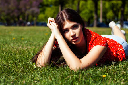 pretty young woman in red dress smiling cheerful in green park on summer sunny day, lifestyle people conceptの写真素材